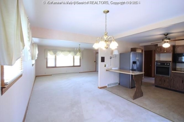 kitchen featuring visible vents, open floor plan, light countertops, black appliances, and a kitchen bar