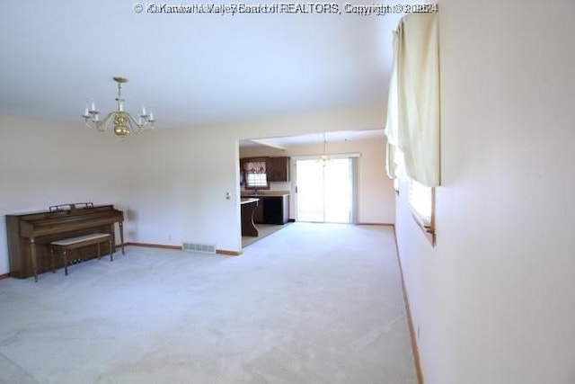 unfurnished living room featuring an inviting chandelier, baseboards, visible vents, and light colored carpet