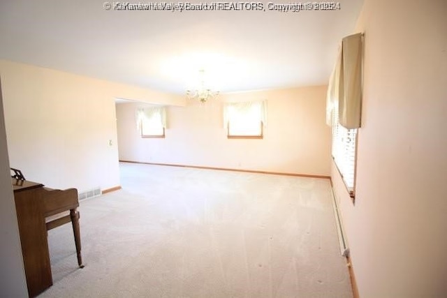 spare room featuring baseboards, an inviting chandelier, visible vents, and light colored carpet