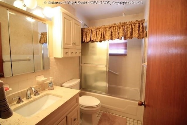 full bath featuring tile walls, bath / shower combo with glass door, tasteful backsplash, toilet, and vanity