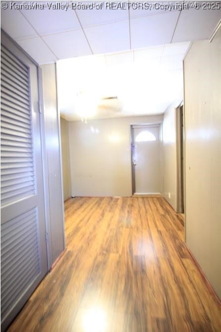 unfurnished room with wood finished floors and a paneled ceiling