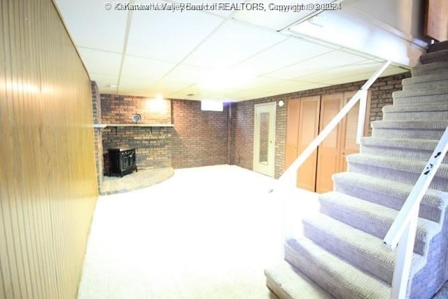 finished basement featuring brick wall, stairway, and a drop ceiling