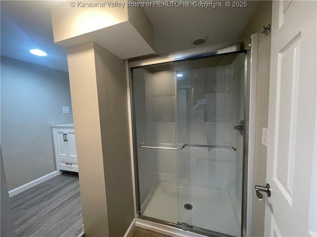 bathroom featuring a stall shower, wood finished floors, and baseboards