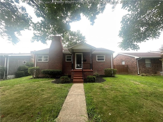 view of front of home featuring a front yard, brick siding, fence, and a chimney