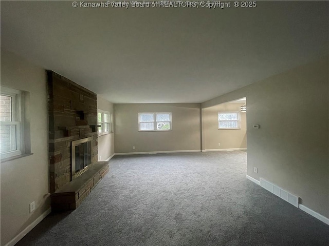 unfurnished living room with carpet flooring, visible vents, a fireplace, and baseboards