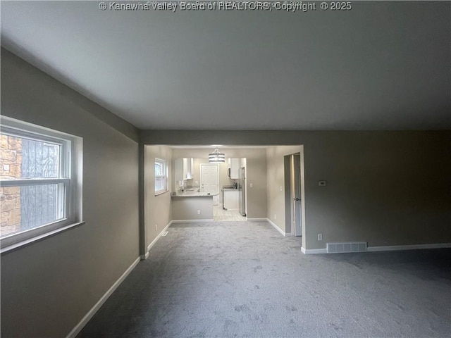 unfurnished living room featuring carpet floors, visible vents, and baseboards