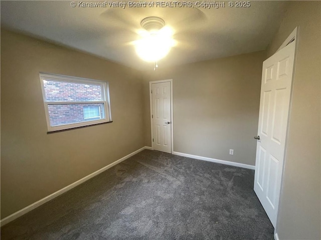 unfurnished bedroom with dark colored carpet and baseboards