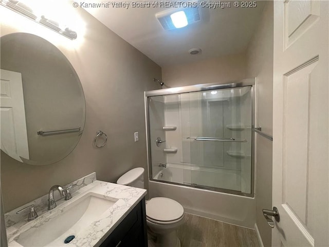 bathroom with toilet, shower / bath combination with glass door, wood finished floors, and vanity