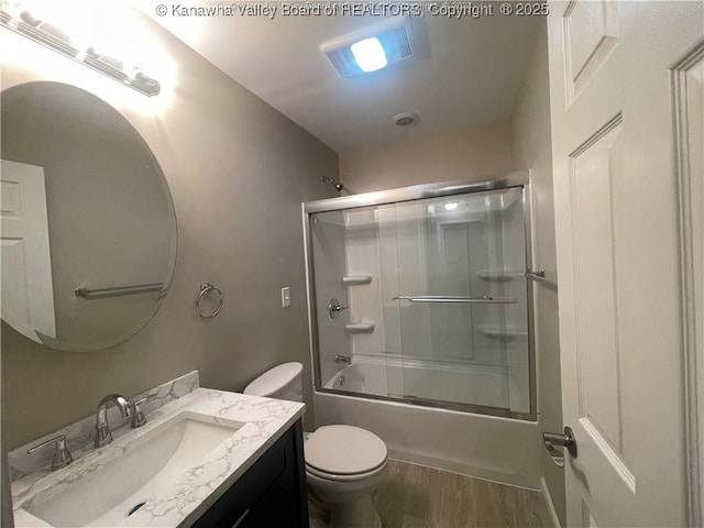 full bathroom with visible vents, toilet, enclosed tub / shower combo, wood finished floors, and vanity