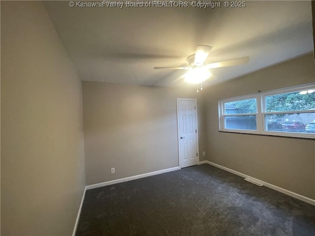 unfurnished room with a ceiling fan, dark colored carpet, and baseboards