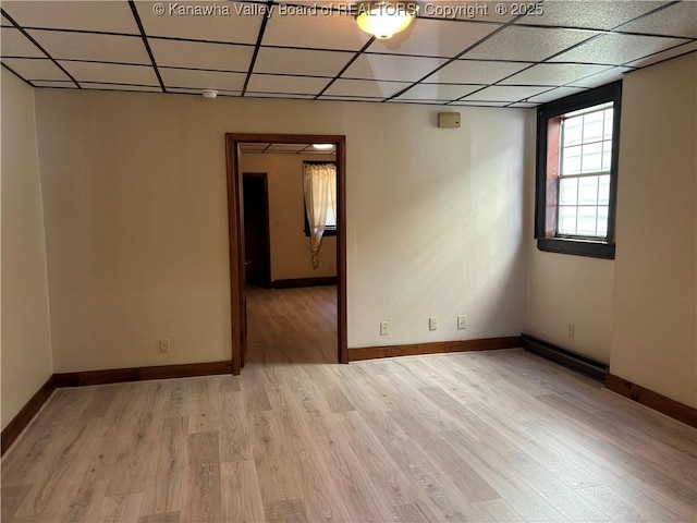 spare room featuring light wood-type flooring, a paneled ceiling, baseboards, and a baseboard radiator