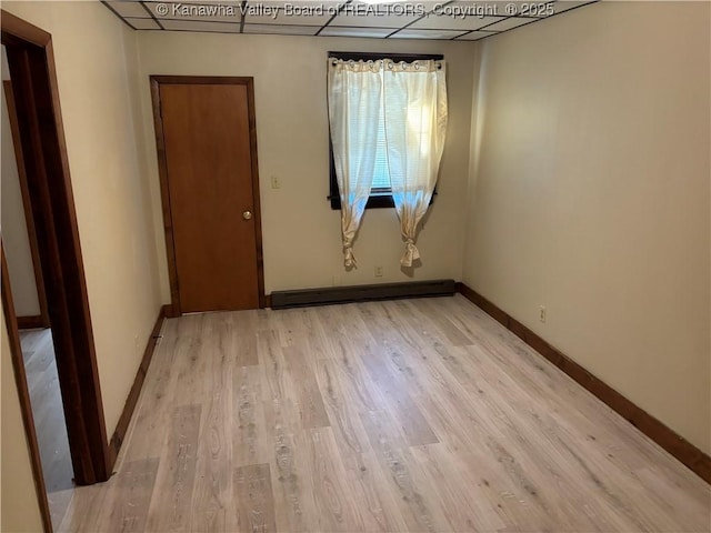 spare room with light wood finished floors, a baseboard radiator, and baseboards