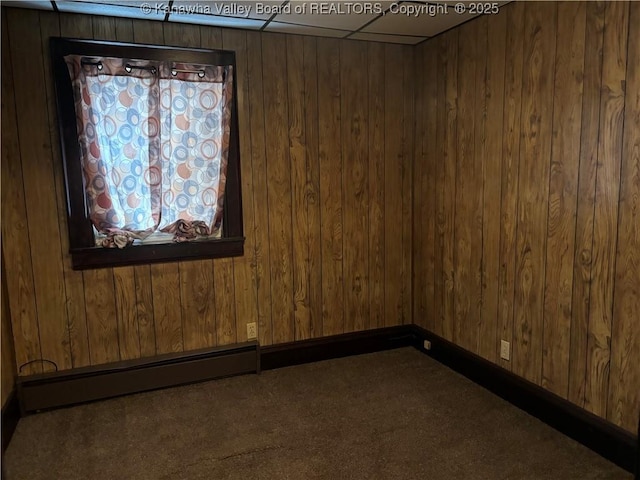 unfurnished room with wood walls, a baseboard radiator, baseboards, and carpet flooring