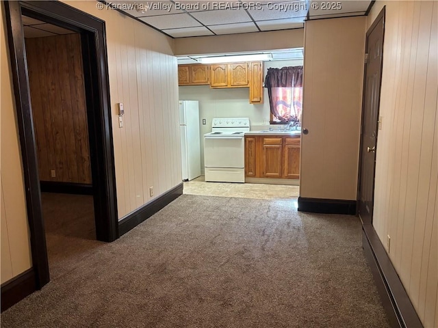 kitchen with white appliances, wooden walls, light countertops, and carpet flooring