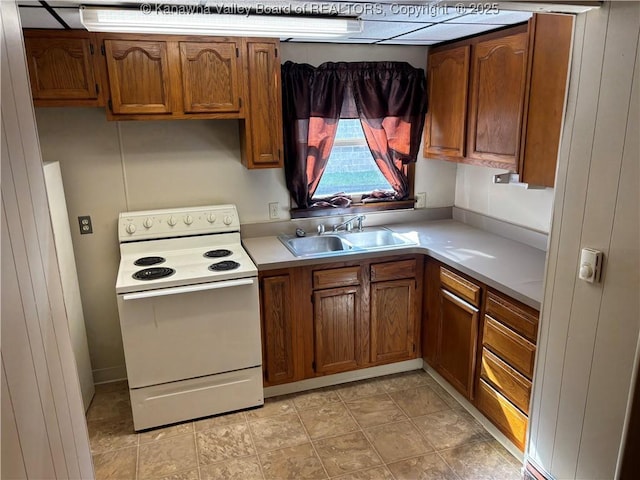 kitchen with brown cabinets, white range with electric stovetop, light countertops, and a sink