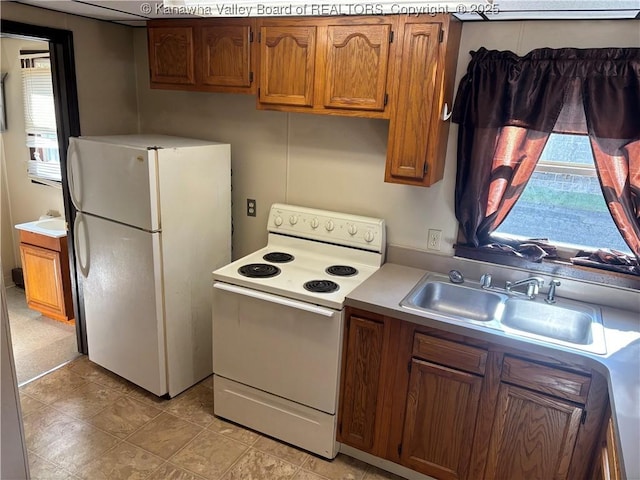 kitchen with brown cabinets, white appliances, light countertops, and a sink