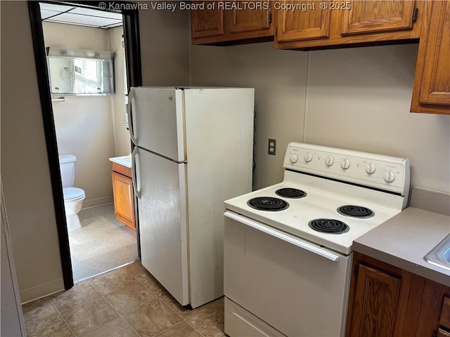 kitchen with brown cabinets, white appliances, and light countertops