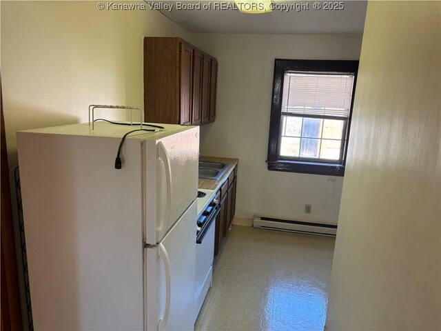 kitchen with stove, a sink, light countertops, baseboard heating, and freestanding refrigerator