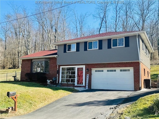 split level home featuring driveway, an attached garage, a front yard, and brick siding