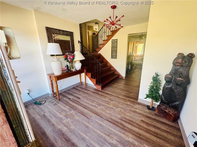 hallway featuring baseboards, a textured ceiling, stairway, and wood finished floors