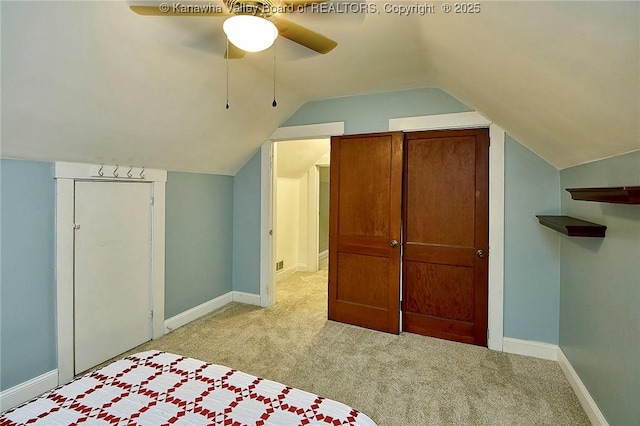 interior space with light carpet, vaulted ceiling, baseboards, and ceiling fan