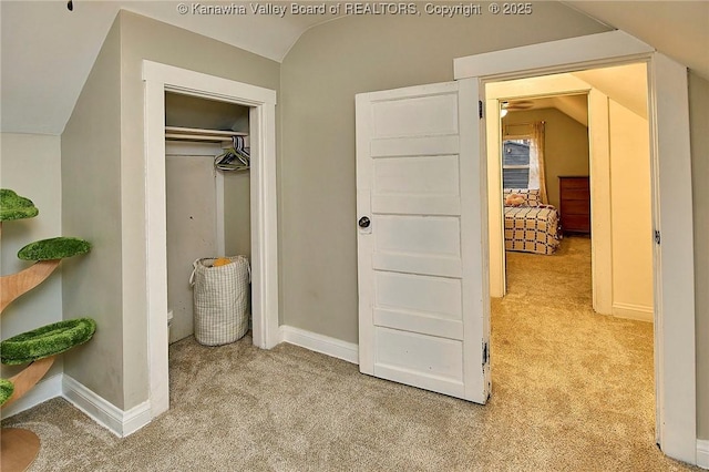 carpeted bedroom with vaulted ceiling, a closet, and baseboards