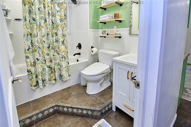 bathroom with wainscoting, vanity, toilet, and shower / bath combo with shower curtain