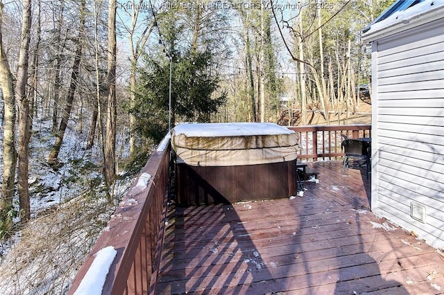 wooden deck featuring a hot tub and a view of trees