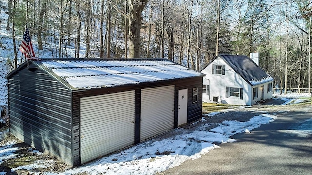 snow covered structure featuring an outbuilding and central AC unit