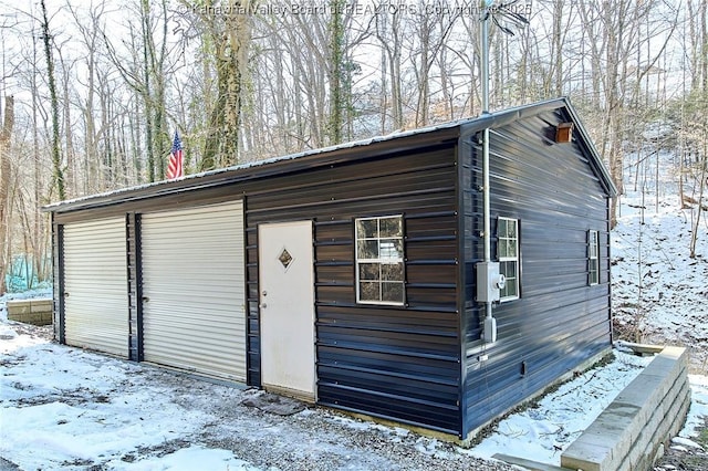 snow covered structure featuring an outbuilding