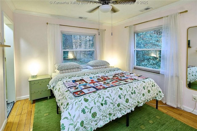 bedroom with ornamental molding, light wood finished floors, multiple windows, and visible vents