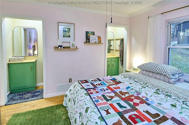 bedroom featuring visible vents, ornamental molding, ensuite bath, wood finished floors, and baseboards