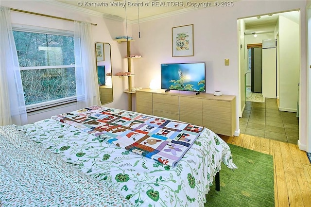 bedroom with crown molding and wood finished floors