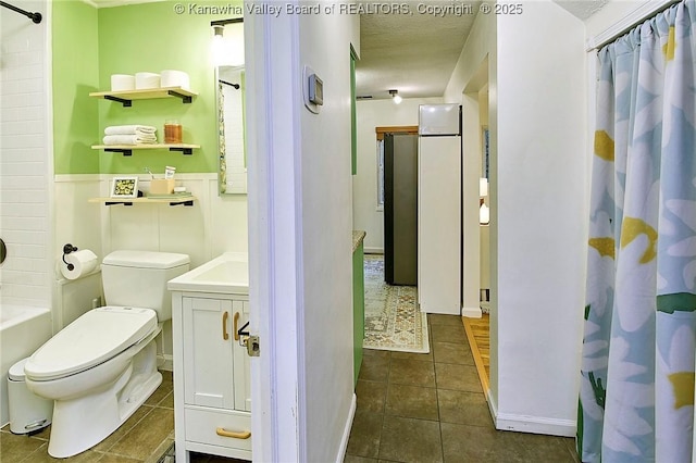 full bathroom with a wainscoted wall, toilet, vanity, a textured ceiling, and tile patterned flooring