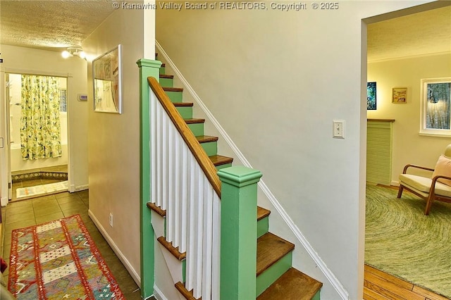 staircase featuring baseboards, a textured ceiling, and tile patterned floors