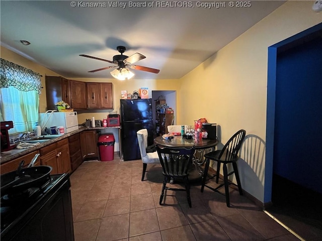 kitchen featuring dark countertops, ceiling fan, tile patterned flooring, black appliances, and a sink