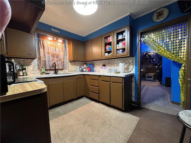 kitchen featuring glass insert cabinets, ornamental molding, a sink, wooden counters, and backsplash