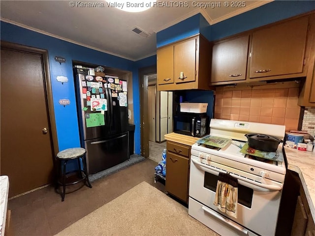 kitchen with decorative backsplash, freestanding refrigerator, light countertops, white range, and black microwave