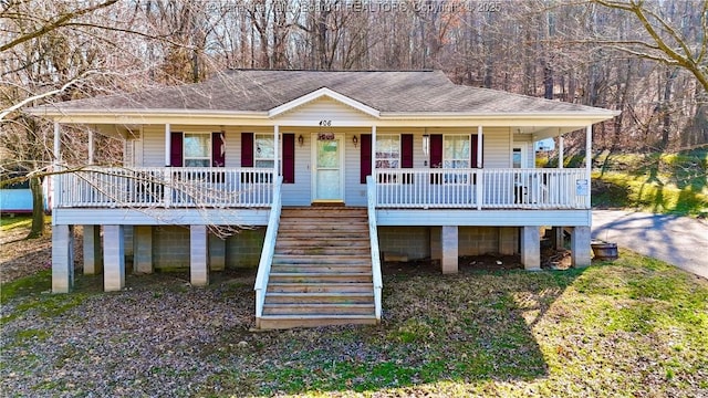 beach home featuring covered porch and roof with shingles