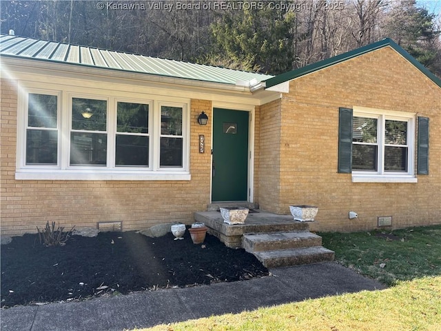 view of front facade with crawl space, metal roof, and brick siding