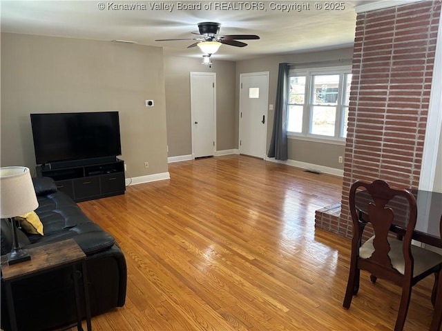 living room featuring visible vents, a ceiling fan, light wood-style flooring, and baseboards