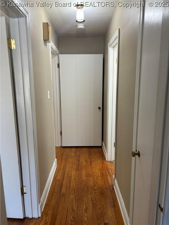 hallway featuring wood finished floors and baseboards