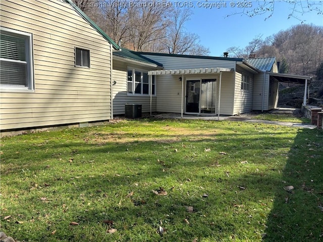 rear view of house with central AC unit, metal roof, and a yard