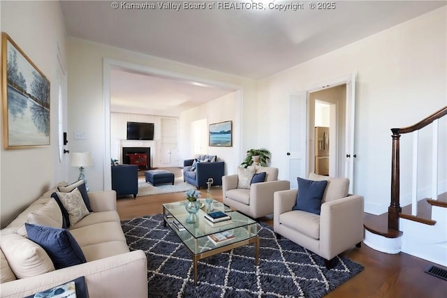 living room with stairs, a fireplace, wood finished floors, and visible vents