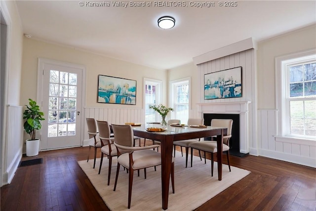 dining area with dark wood-style flooring, wainscoting, a fireplace, and visible vents