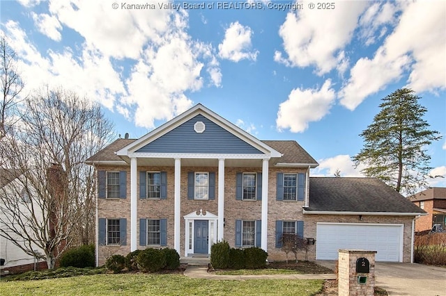 neoclassical home featuring an attached garage, a front yard, concrete driveway, and brick siding