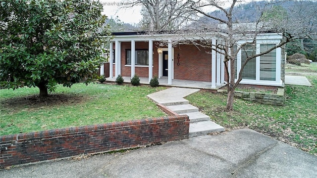 view of front facade featuring covered porch, brick siding, and a front lawn