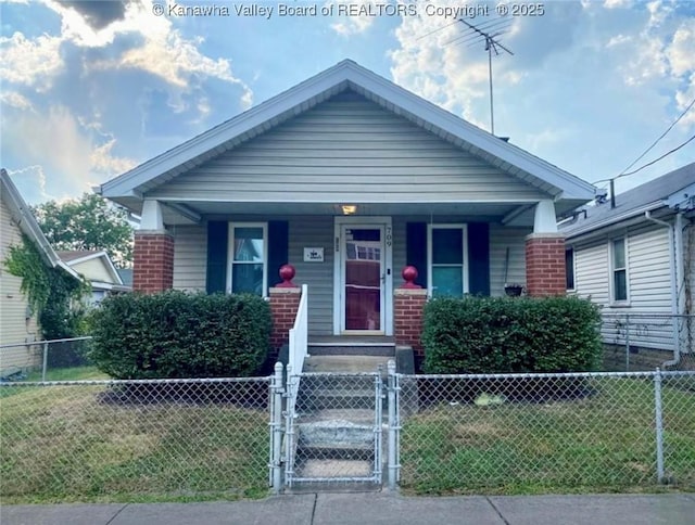 view of front of property featuring a fenced front yard, covered porch, brick siding, and a gate