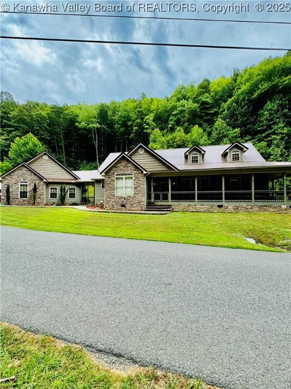 view of front of property featuring a front lawn and a wooded view