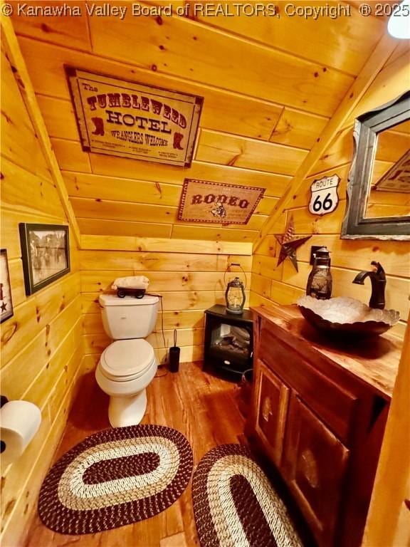 2299 Striker Fork Rd, Chapmanville, WV 25508 - half bathroom with vanity, toilet, wood walls, vaulted ceiling, and wood finished floors